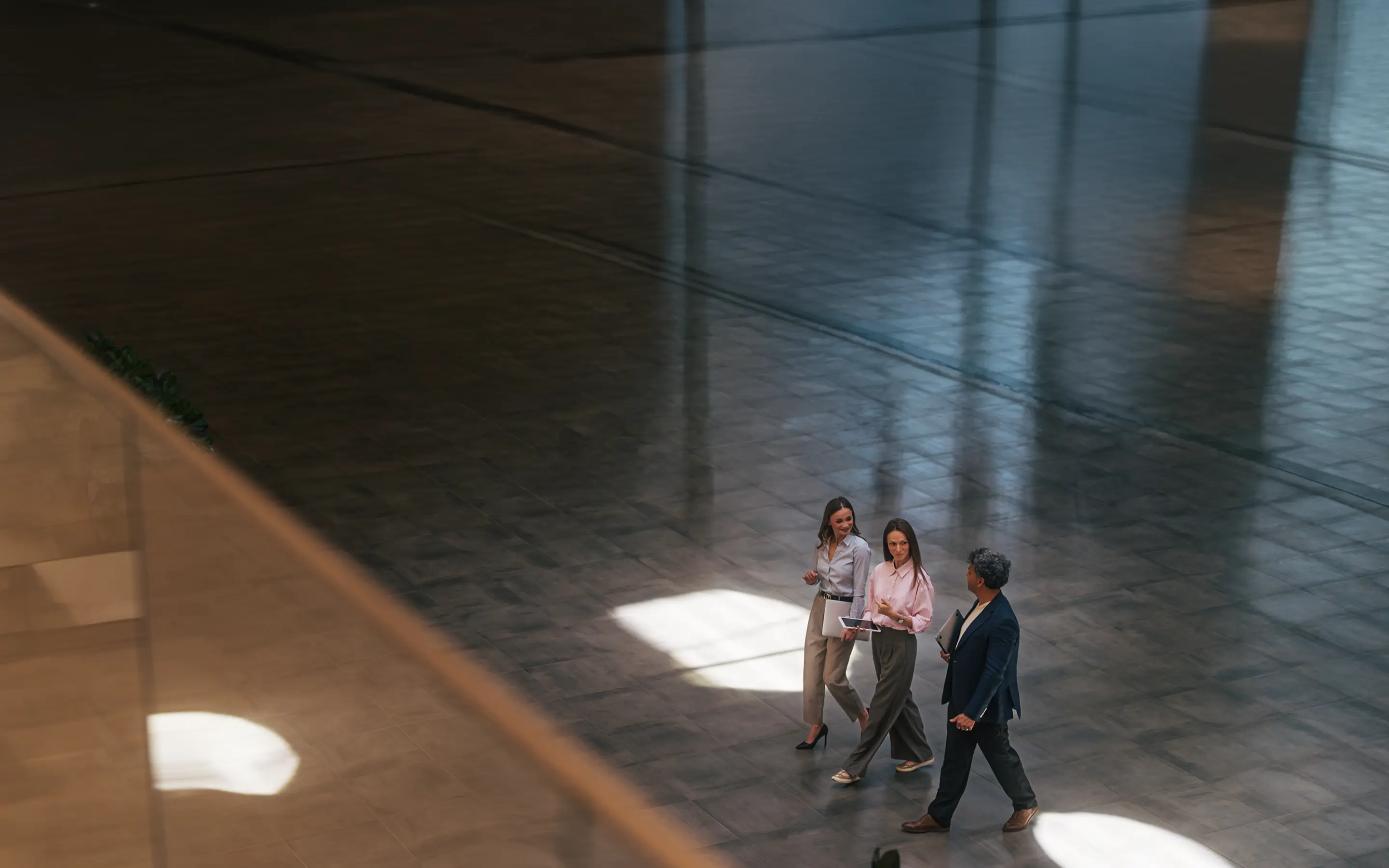 Three professionals walking through a grand, dimly lit lobby.