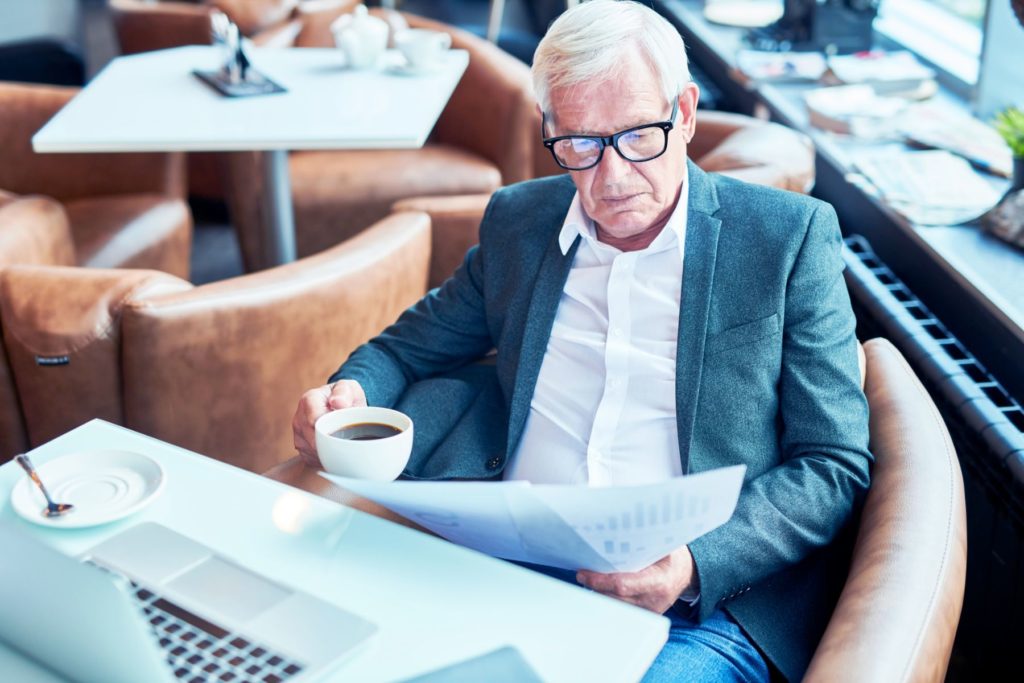 Retired man reviewing personal paperwork over coffee