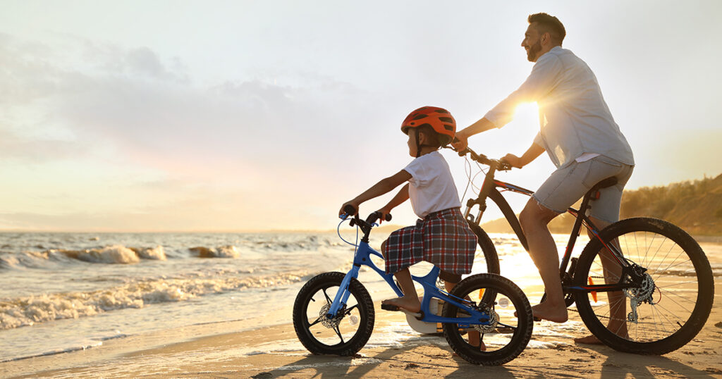 Father and son riding bikes on beach