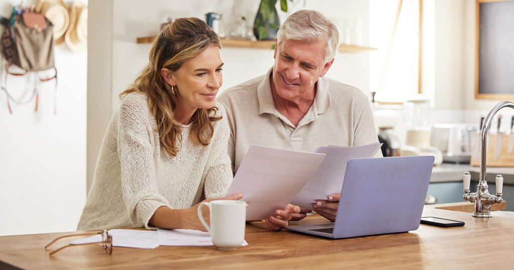 Couple looking at documents together on kitchen counter.