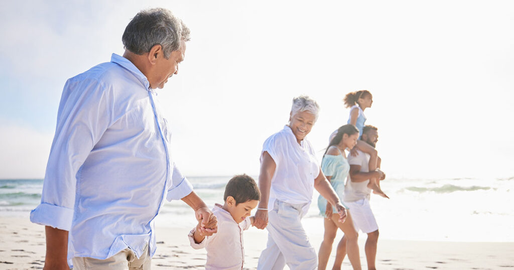 Multigenerational family holding hands walking on beach