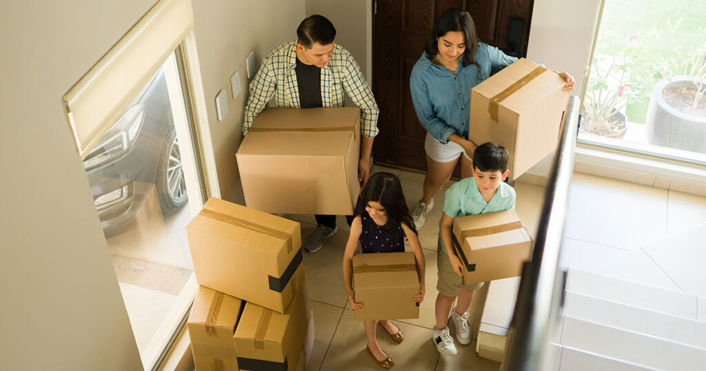 Young family with parents and two children that are moving boxes