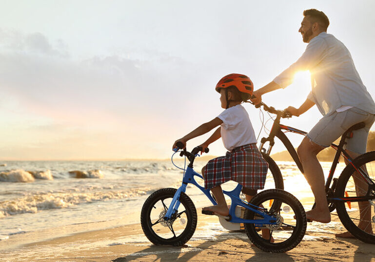 Father and son riding bikes on beach