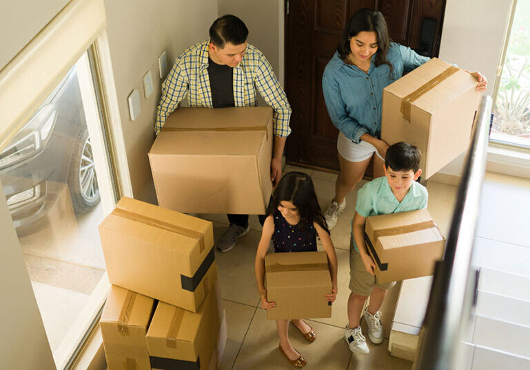 Young family with parents and two children that are moving boxes