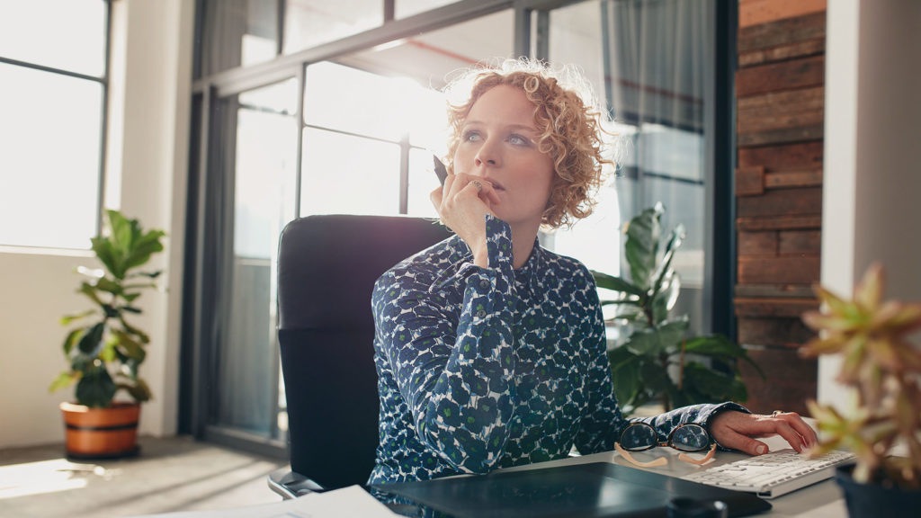 Woman sitting at desk contemplating future