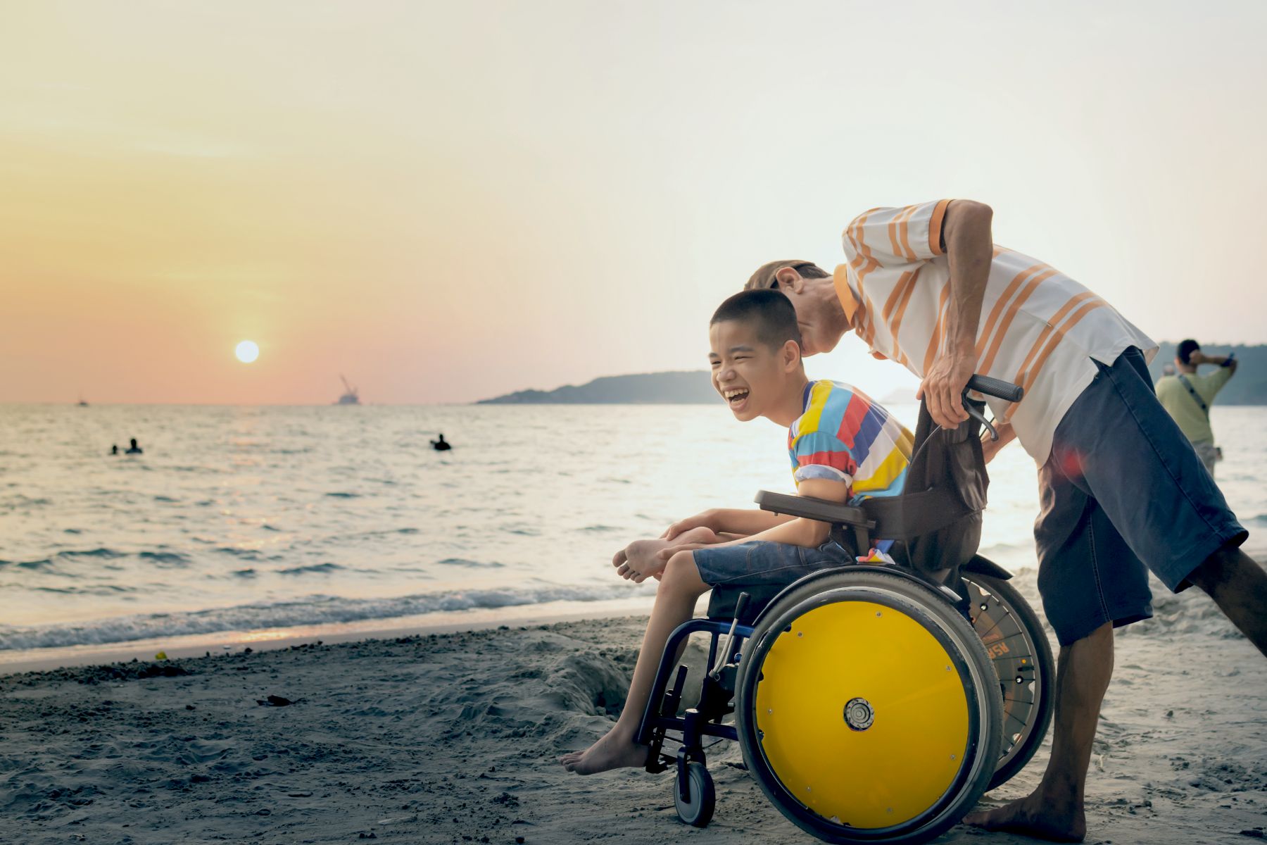 Laughing boy in wheelchair on beach