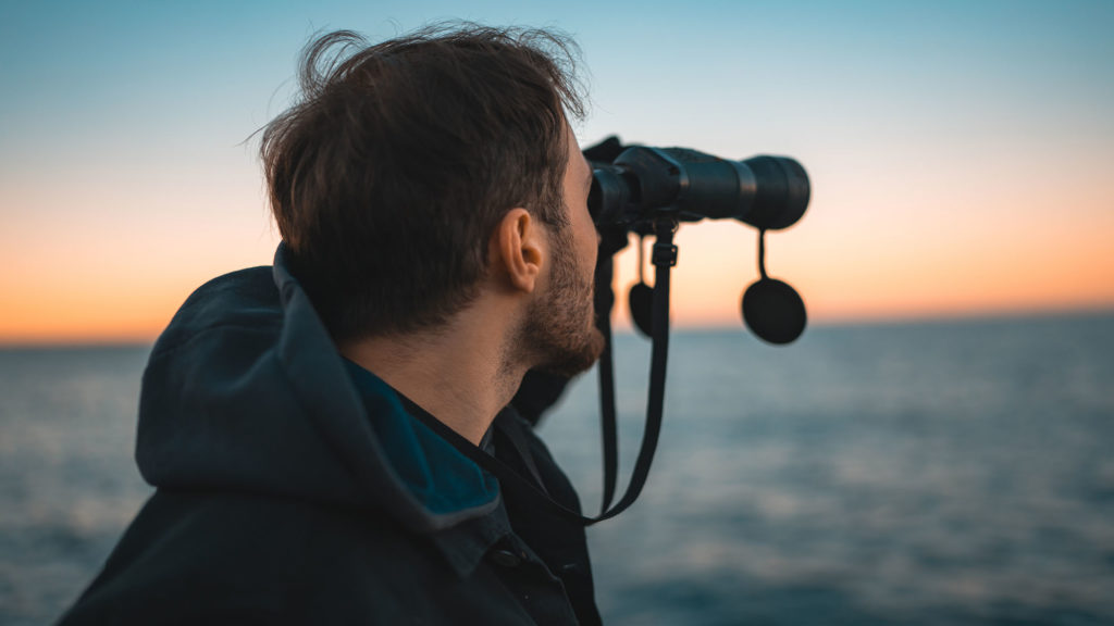 Man using binoculars to view the rough sea