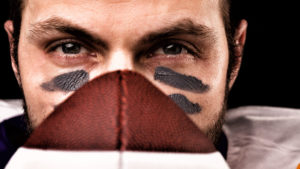 Portrait of american college football player holding a ball and looking at camera