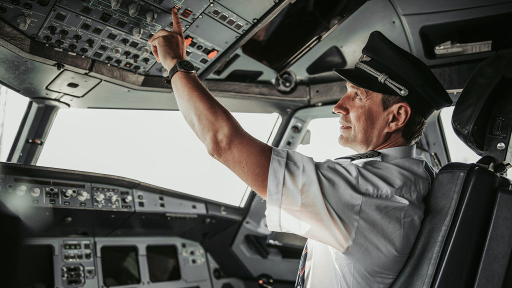Man in uniform pushing button in cabin during flight stock photo. Airways concept