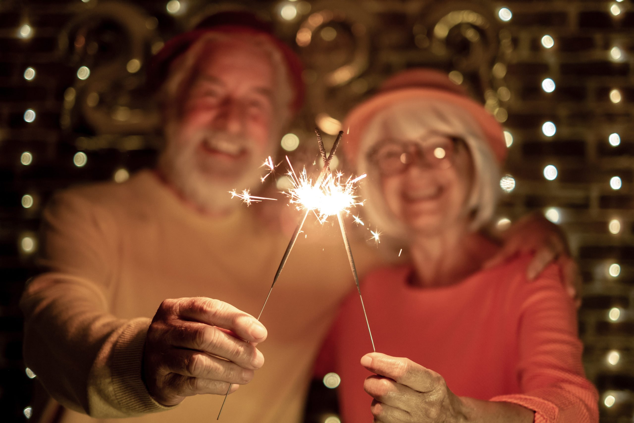 senior couple holding sparklers celebrating new year