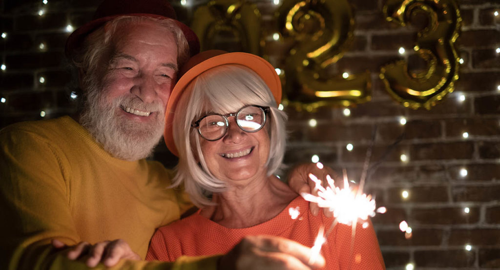 senior couple holding sparklers celebrating New Years 2023