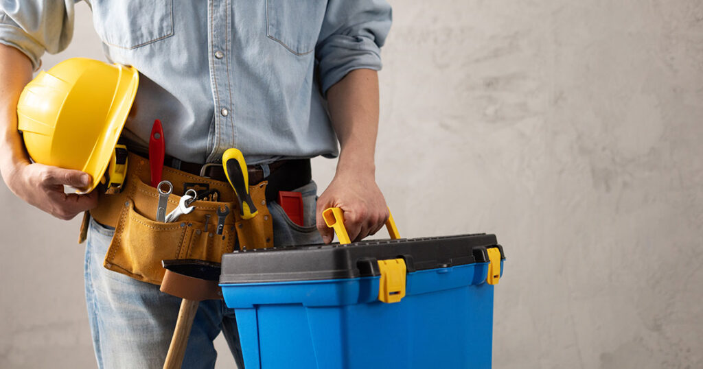 Construction worker holding tools and toolbox.