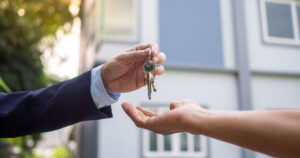 Person handing keys to another person.