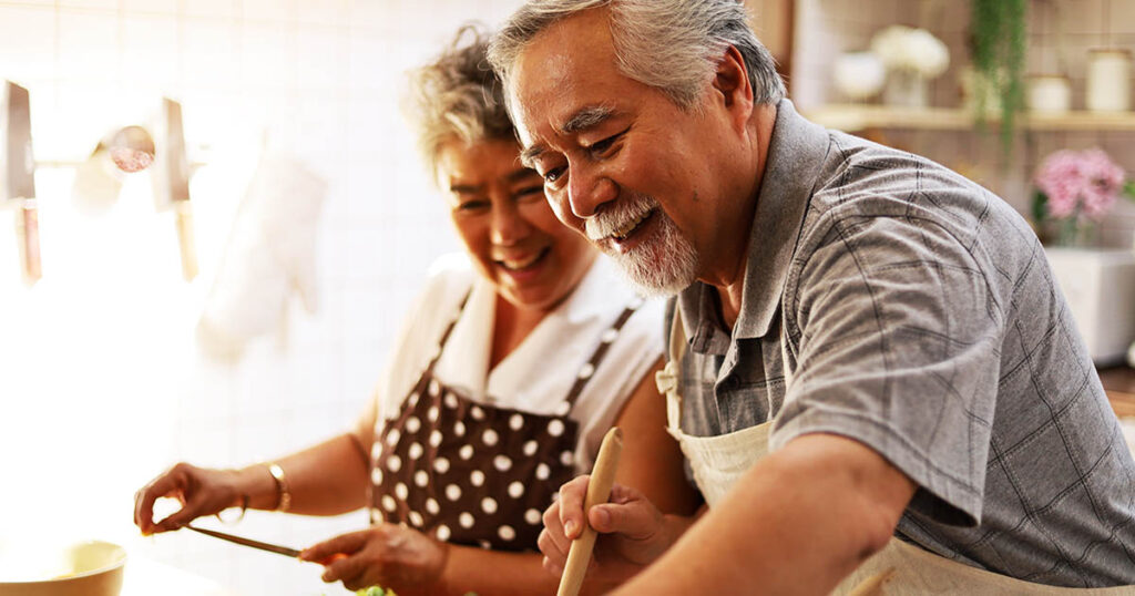 Happy couple in kitchen hopes their savings will last throughout retirement