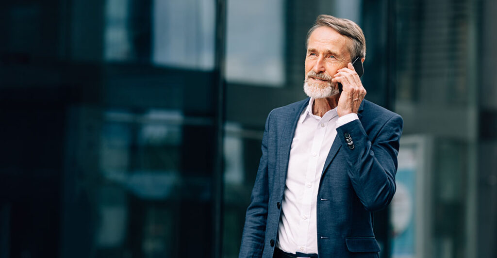 High-net-worth investor in a suit talking on the phone outside a modern office building, representing 2026 private market investing strategies for growth