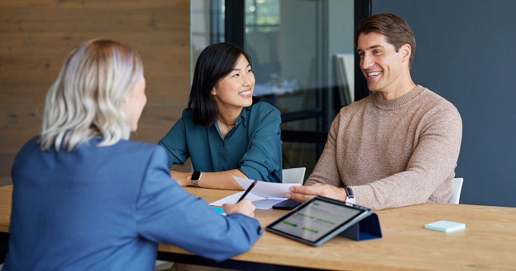 Financial advisor meeting with a couple to discuss financing options and community development projects related to New Markets Tax Credits.