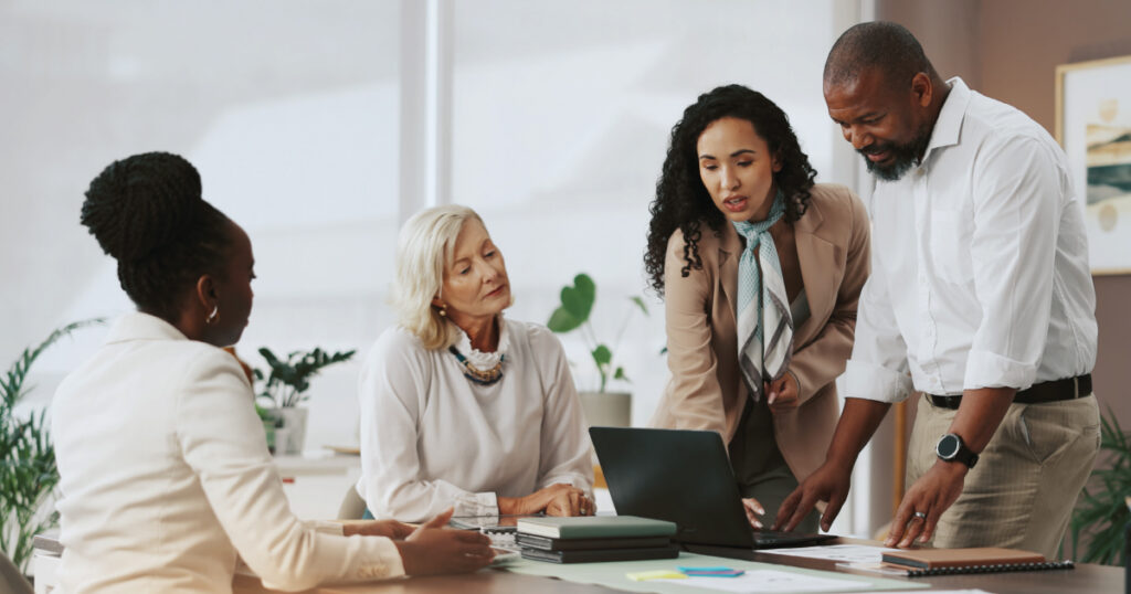 Business team collaborating around a laptop in a modern office, discussing strategy for a single family office.