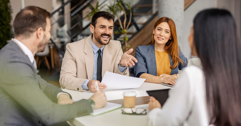 Team of financial advisors meeting with a couple in a modern office, discussing multi-family office structure, services and fees