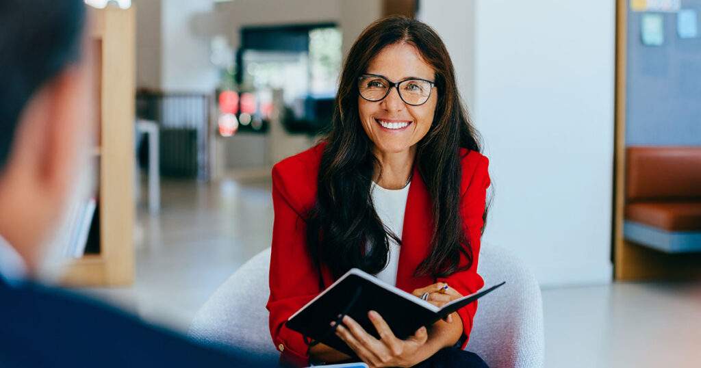 Female advisor in red blazer meeting with client to discuss family office wealth management strategy