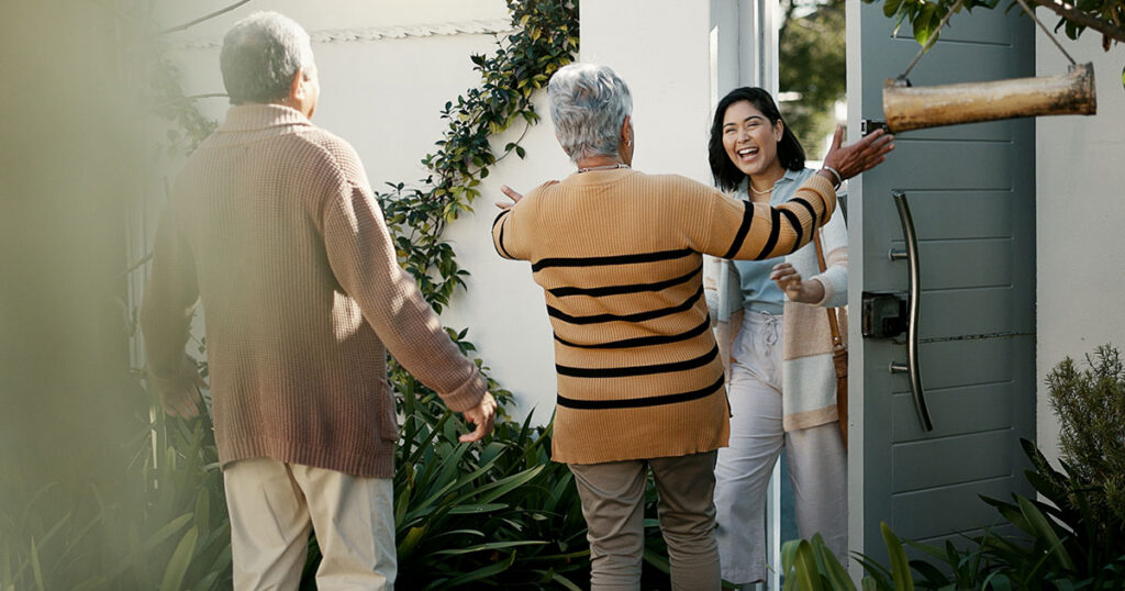 Older parents warmly greeting their adult daughter at the front door, symbolizing family support and the importance of setting healthy boundaries when financially helping grown children.