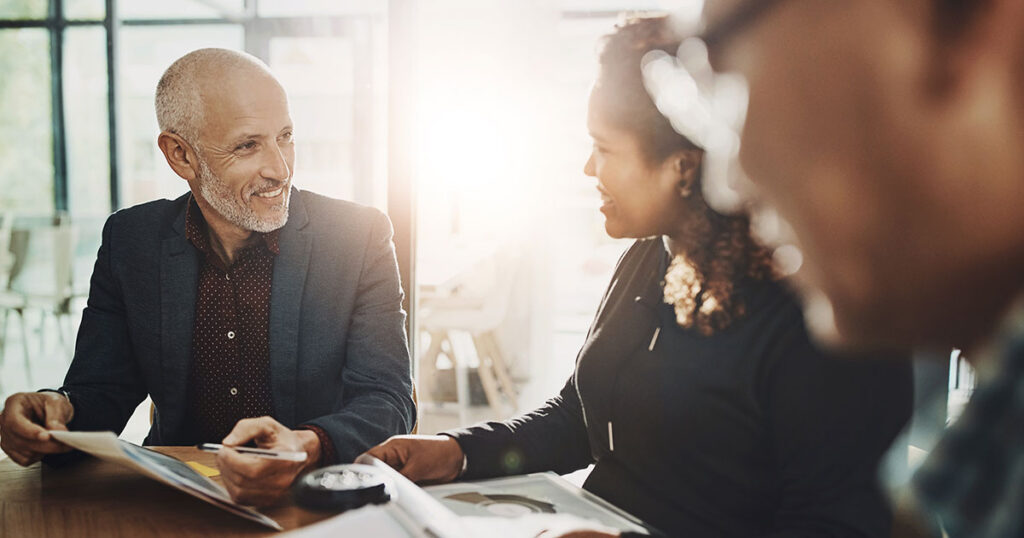 Wealth advisor meeting with ultra-high-net-worth clients in a bright modern office, reviewing tax and estate planning documents together at a conference table to discuss multigenerational wealth strategies.