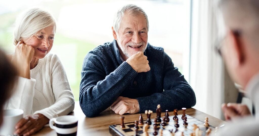 Ultra-high-net-worth family members in a thoughtful conversation over a chessboard, symbolizing the emotional and strategic decisions involved in managing significant family wealth.