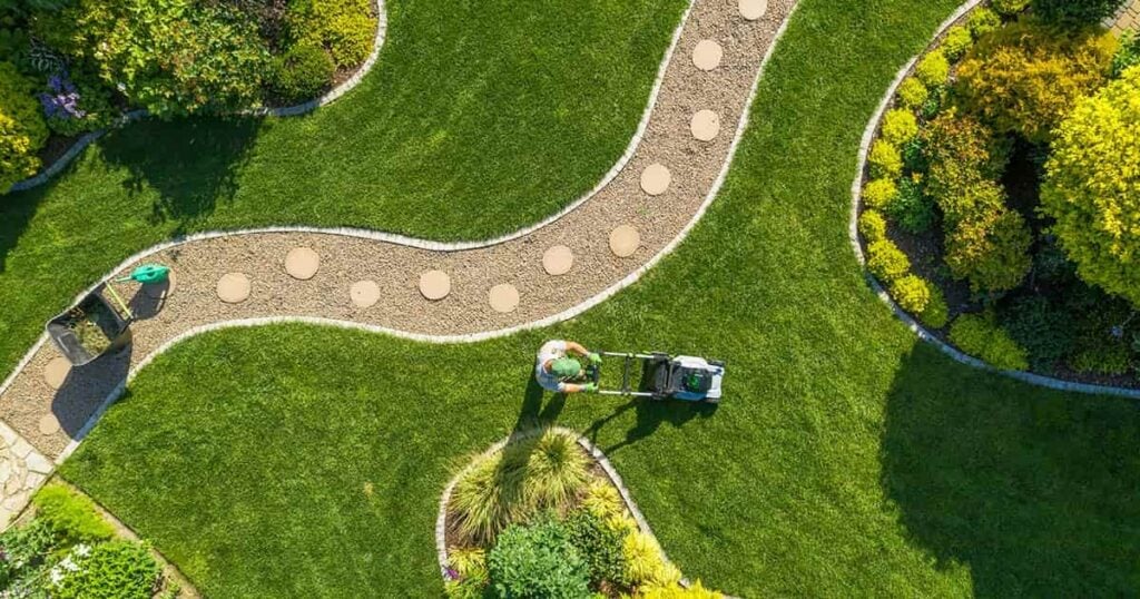 A professional landscaper mowing a neatly manicured lawn, illustrating how outsourcing routine work like accounting lets small business owners focus on growth.