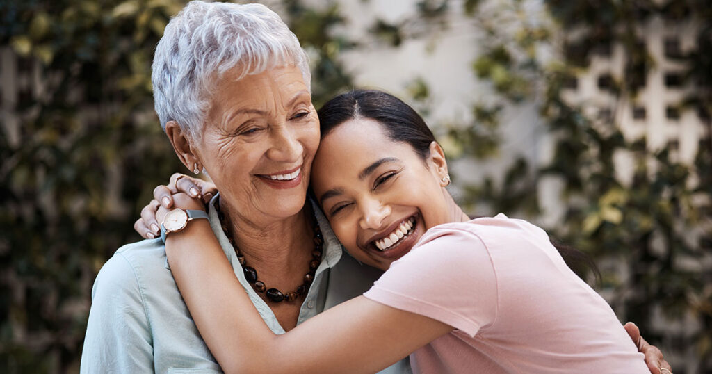 Adult child hugging an older parent outdoors, symbolizing family legacy, multigenerational planning and the impact of 2025 estate tax exemption rules on future inheritances