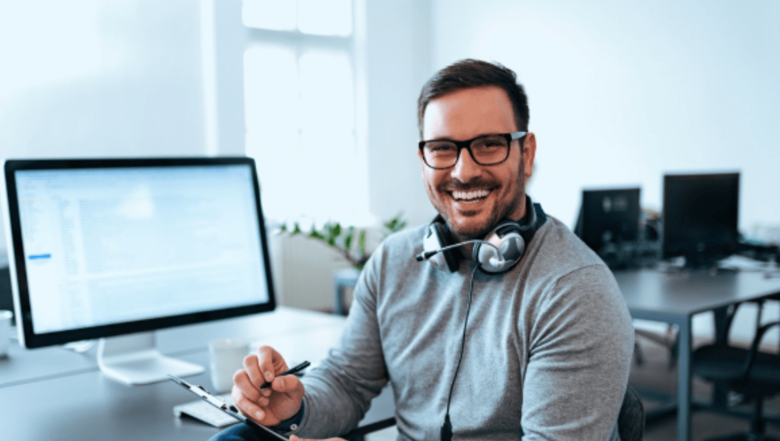  A smiling financial professional at his desk with a headset, representing the single coordinated relationship Creative Planning offers to high-net-worth business owners.