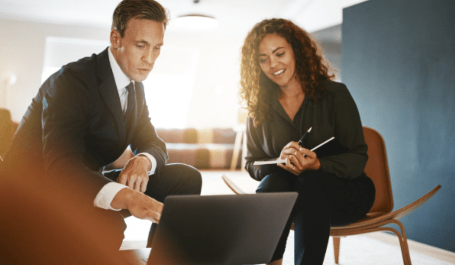  A financial advisor showing a comprehensive wealth plan on a laptop to a business owner client during a consultation.