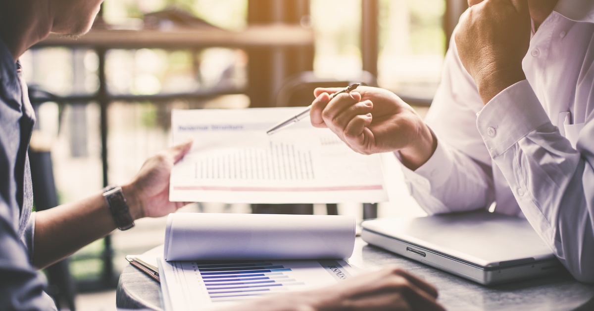 Two people reviewing financial documents and charts during a business meeting.