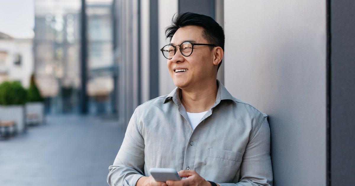 Professional individual holding a smartphone outdoors, representing QSBS investment opportunities and strategic tax planning