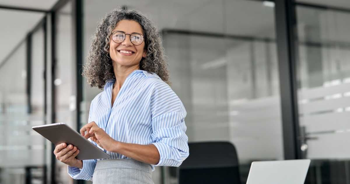 Tech professional standing in a modern office holding a tablet, representing thoughtful planning for RSUs, stock options and concentrated equity compensation