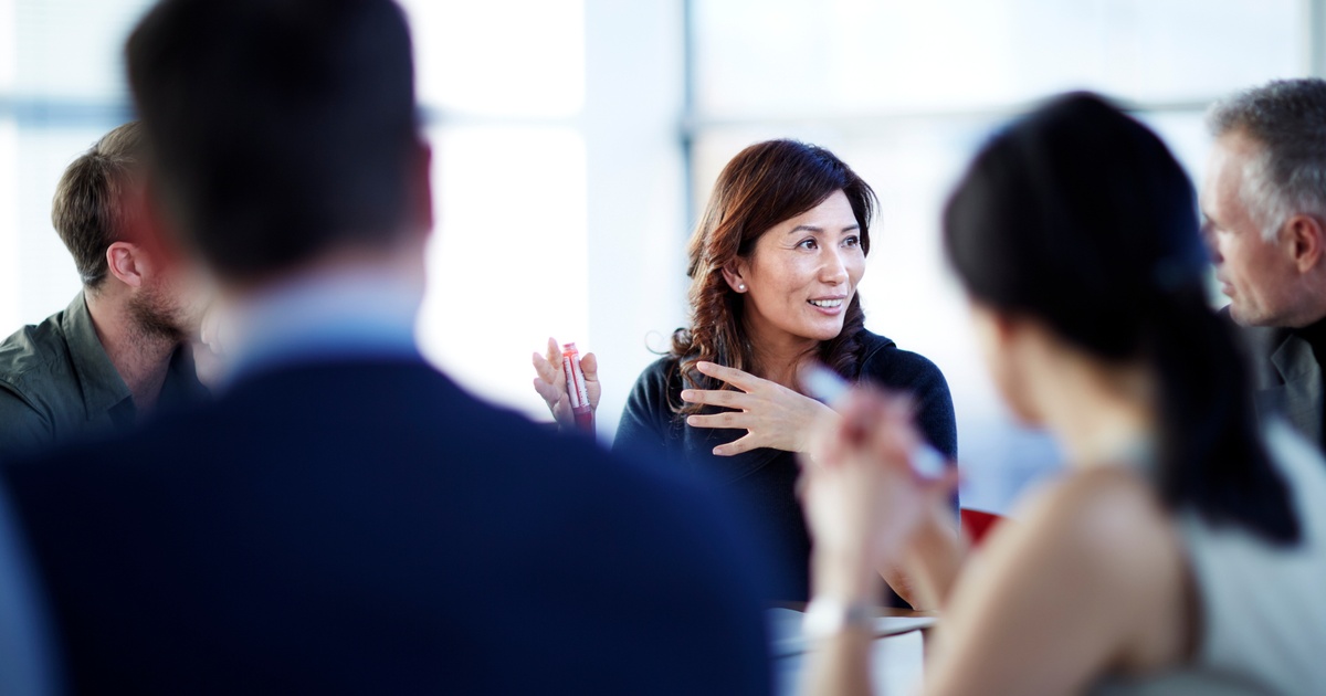 A diverse group of professionals in a meeting discussing financial and equity planning questions with an advisor.