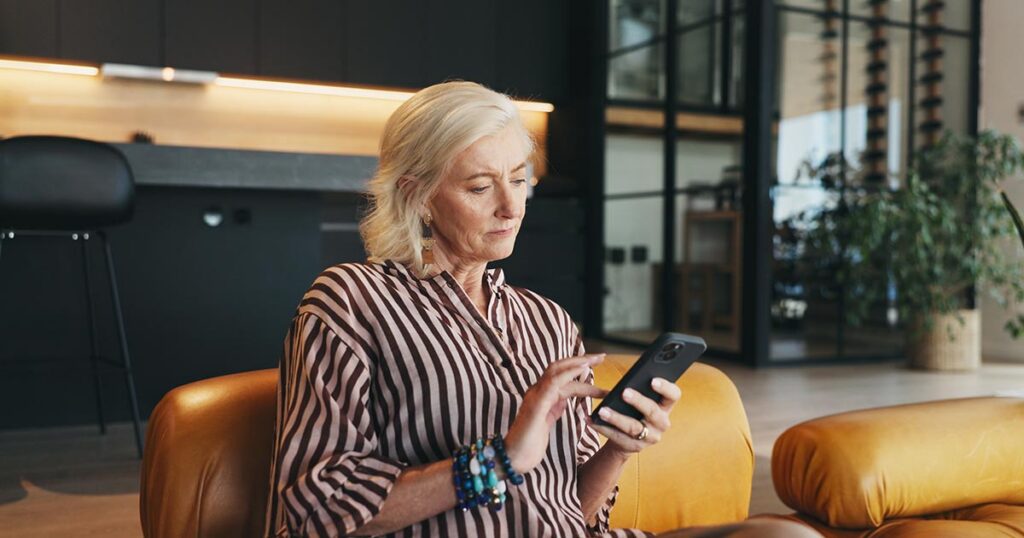 Woman carefully reviewing a message on her smartphone at home, illustrating personal vigilance and fraud prevention against financial crime and digital scams
