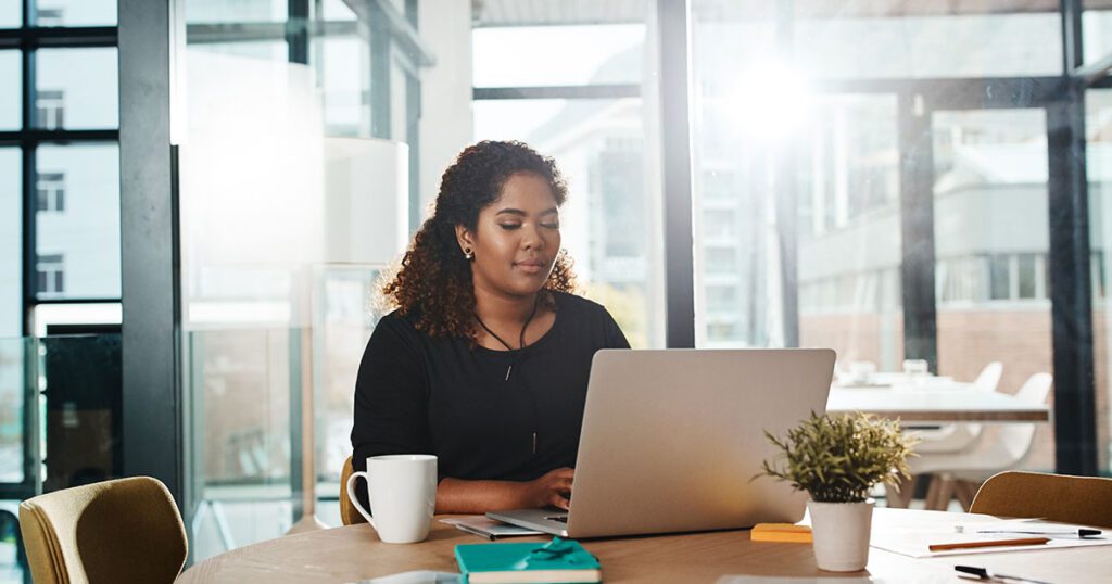 Woman working on a laptop in an office reviewing an email to identify potential phishing scams