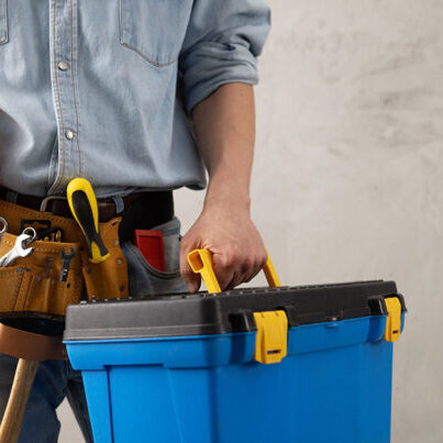 Construction worker holding tools and toolbox.