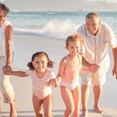 Retired couple with granddaughters enjoying time on a beach.