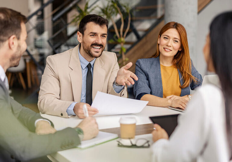 Team of financial advisors meeting with a couple in a modern office, discussing multi-family office structure, services and fees
