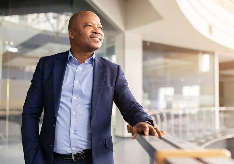 Confident business founder or executive standing in a modern corporate office, representing equity compensation planning with an 83(b) election and QSBS strategy.