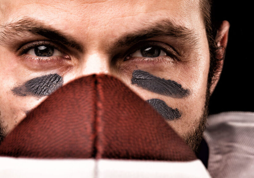 Portrait of american college football player holding a ball and looking at camera