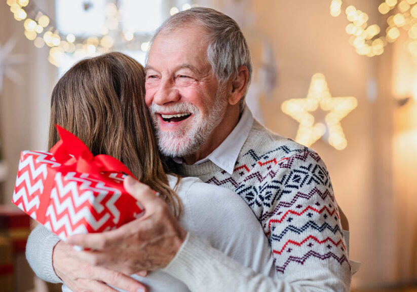 Senior man giving present to young woman on Christmas