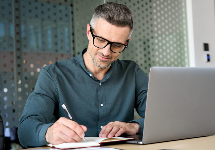 Happy mature man reviewing finances and taking notes