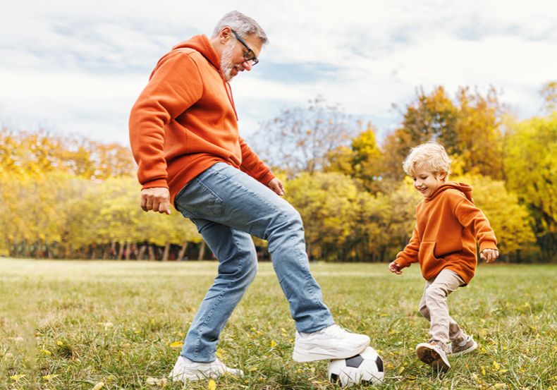 Relaxed grandfather plays soccer with young grandchild