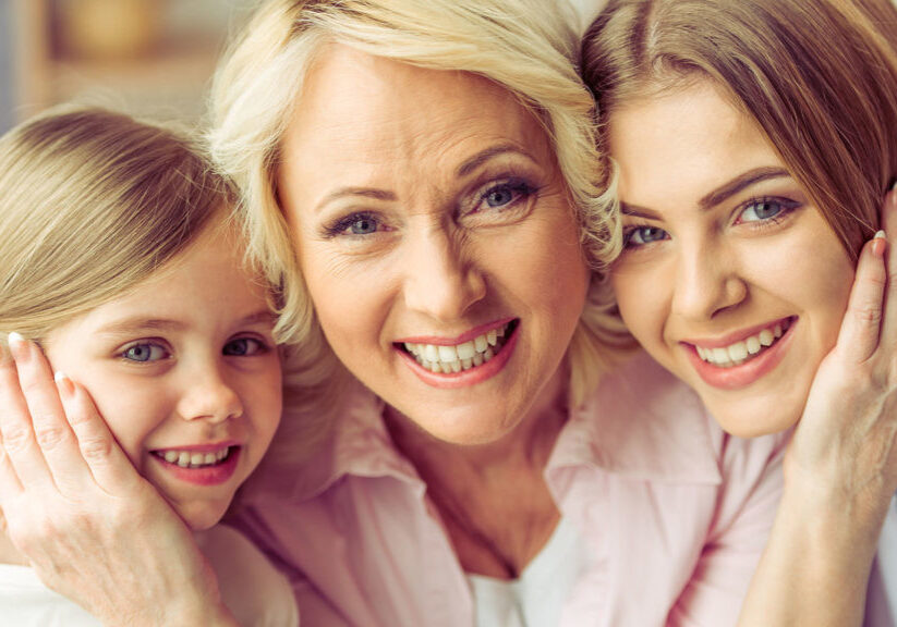 Portrait of three generations of happy beautiful women looking at camera, hugging and smiling