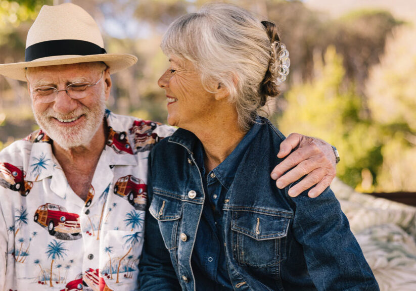 Happy senior couple smiling cheerfully while relaxing at a spa resort. Romantic elderly couple enjoying their summer vacation together. Grey-haired couple enjoying life after retirement.