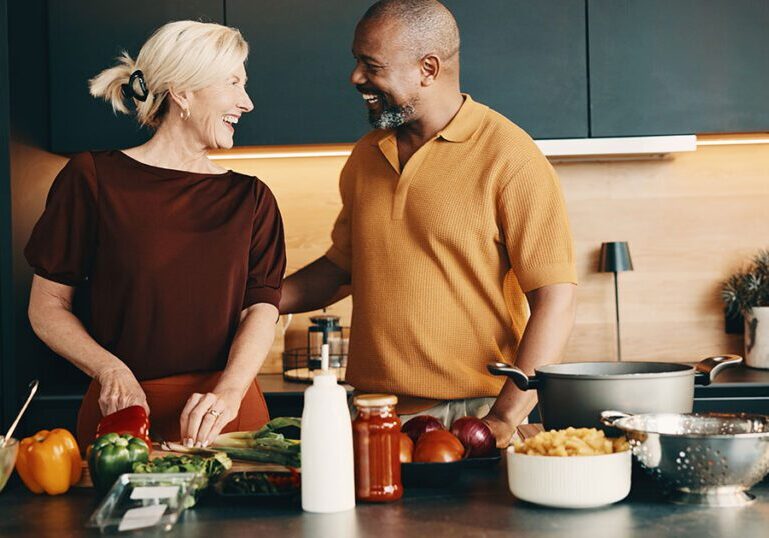 Couple laughing together while cooking in a modern kitchen, illustrating proactive tax planning strategies for long-term financial security.